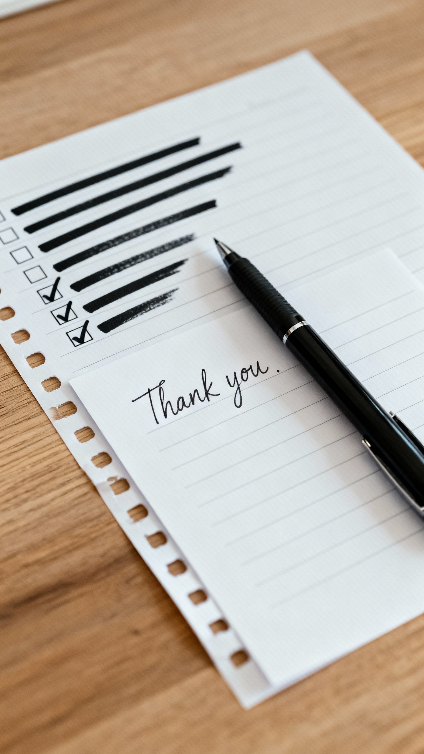 Desk scene with checklist and bold strikethroughs, thank-you note, single pen