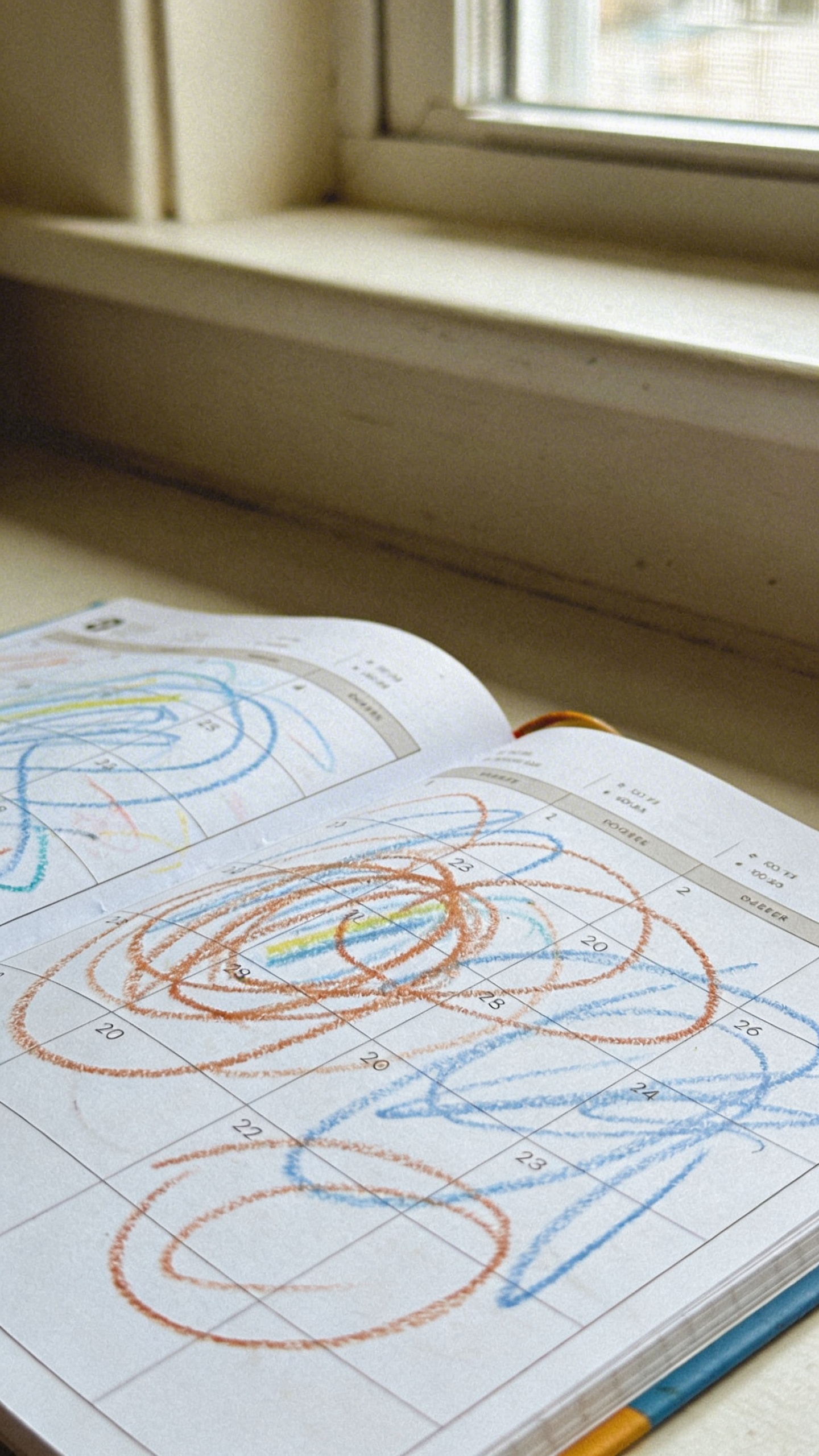 Open planner with toddler crayon scribbles, soft window light