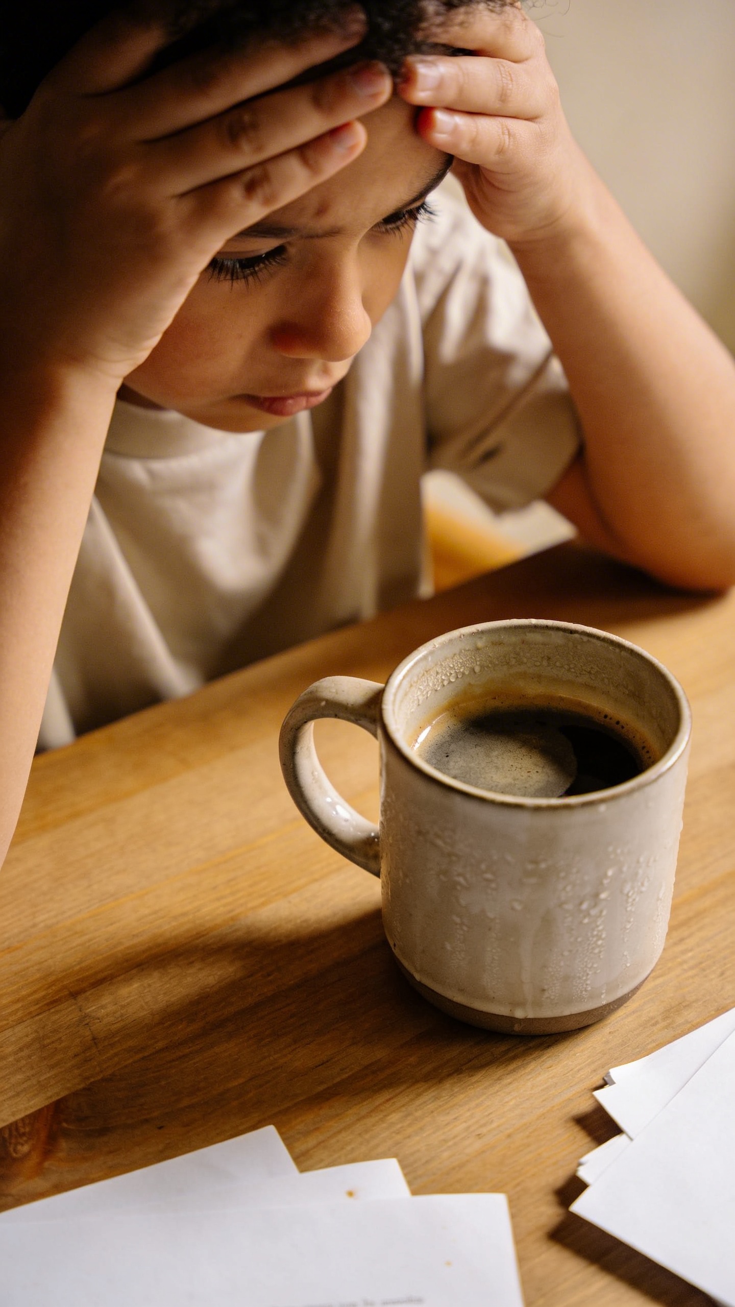 stressed parent rubbing temples beside cold coffee mug