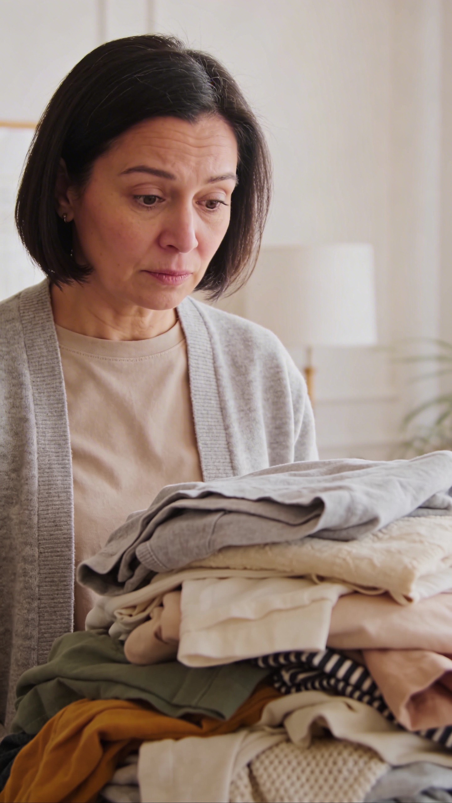 Mom staring at laundry pile, blank expression, soft daylight