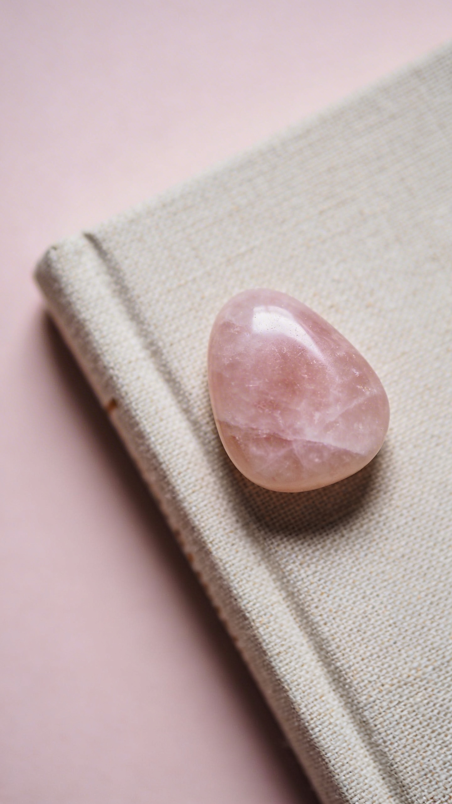 rose quartz worry stone on linen journal, minimal macro shot