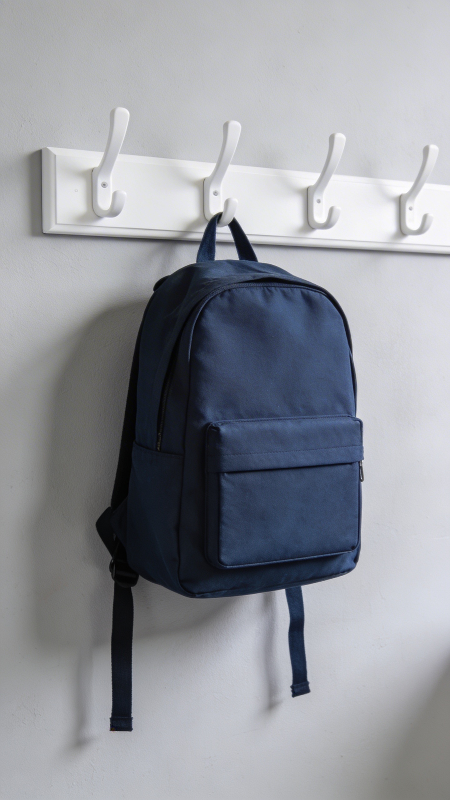 minimalist white entryway hook with one labeled school backpack
