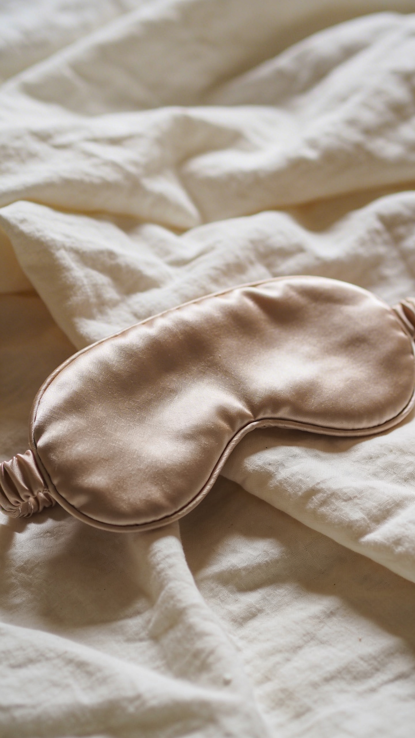 closeup of a silk eye mask on rumpled bedsheet