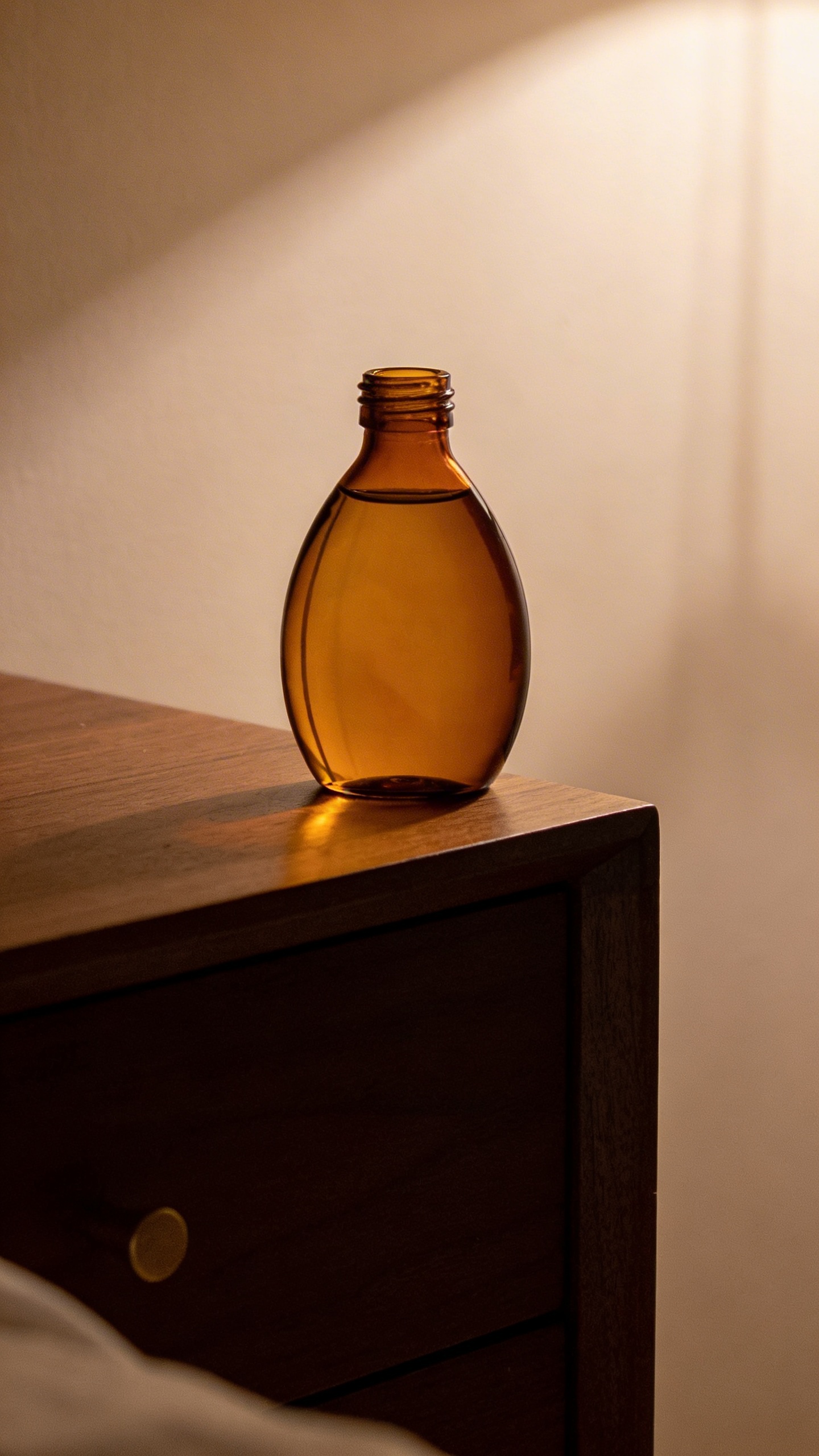 single amber bottle of personal lubricant on nightstand