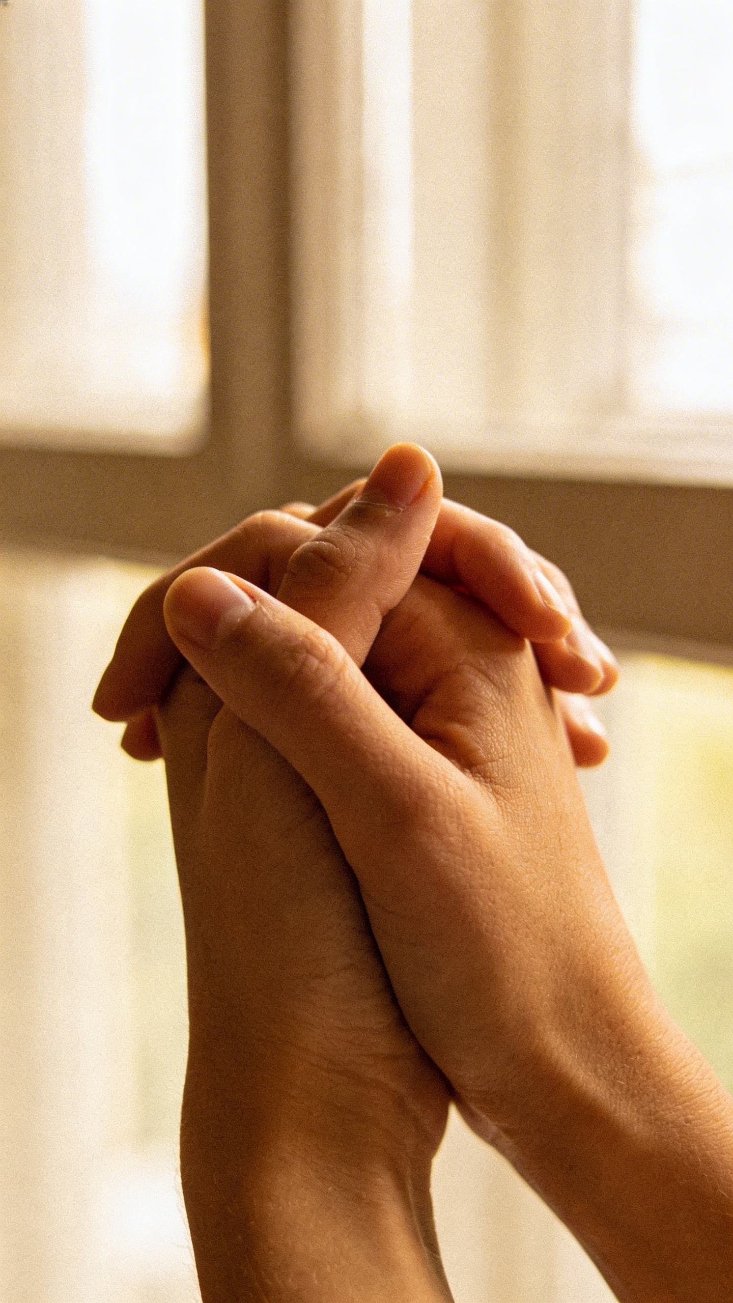 closeup of clasped hands loosening, soft window light