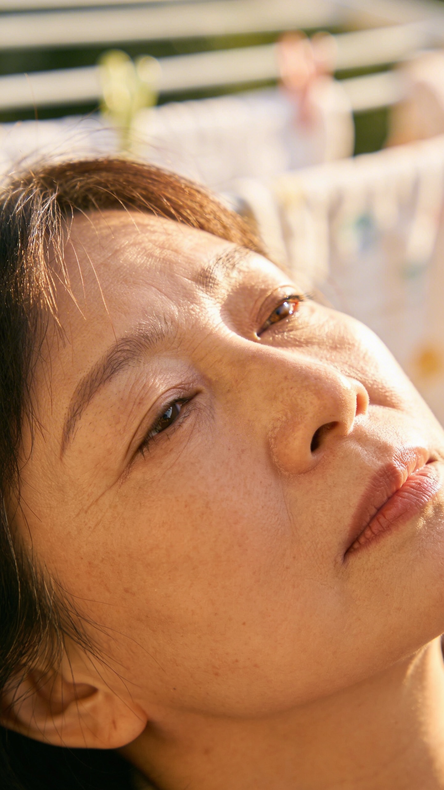 tired mother’s face, soft morning light, laundry blur bokeh