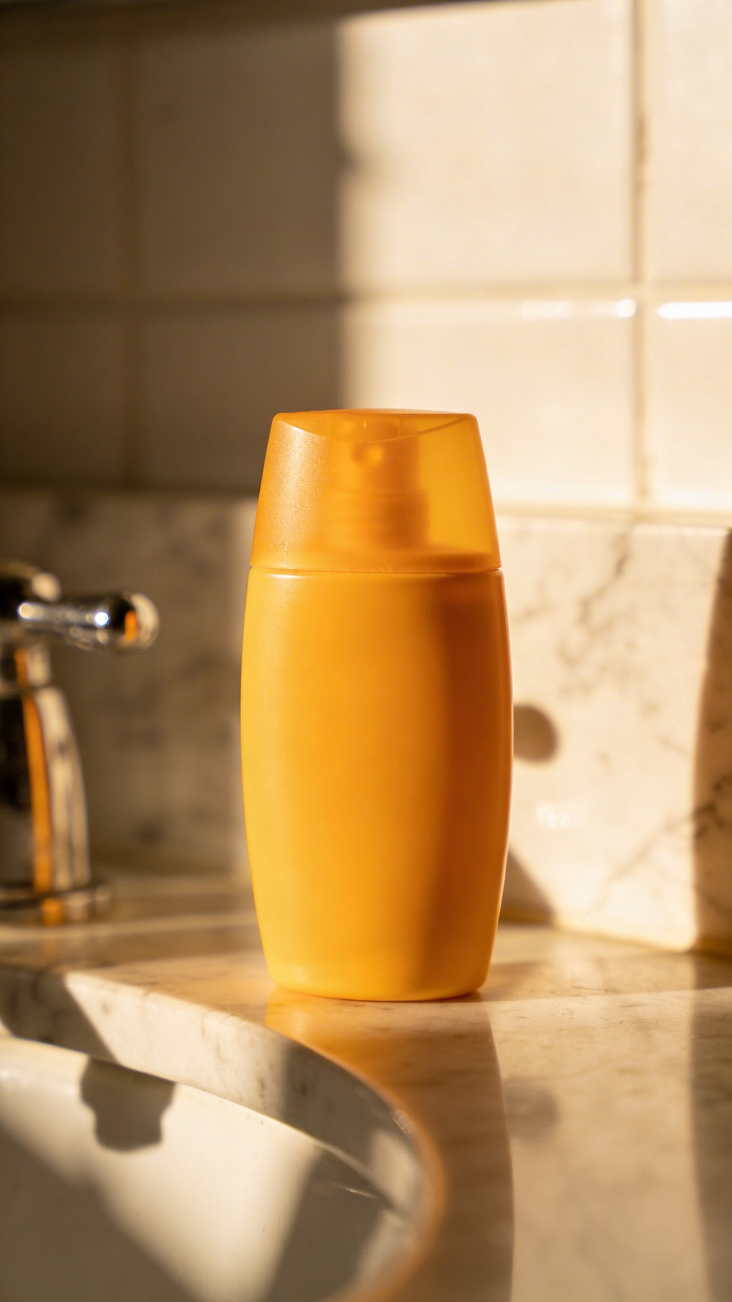 single sunscreen bottle with morning light on bathroom counter