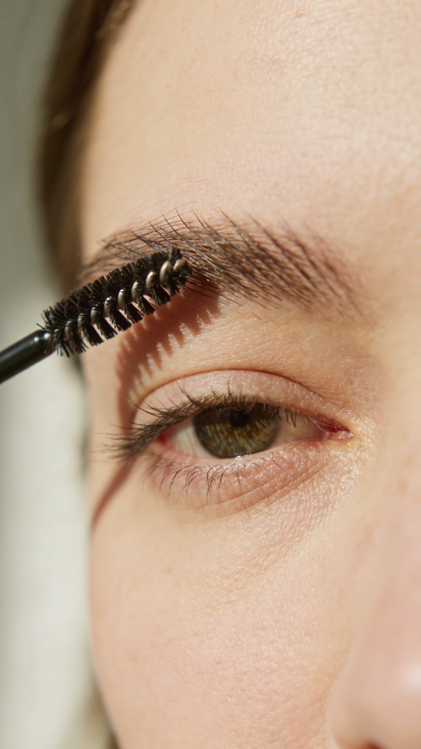 eyebrow spoolie grooming one brow, soft daylight closeup