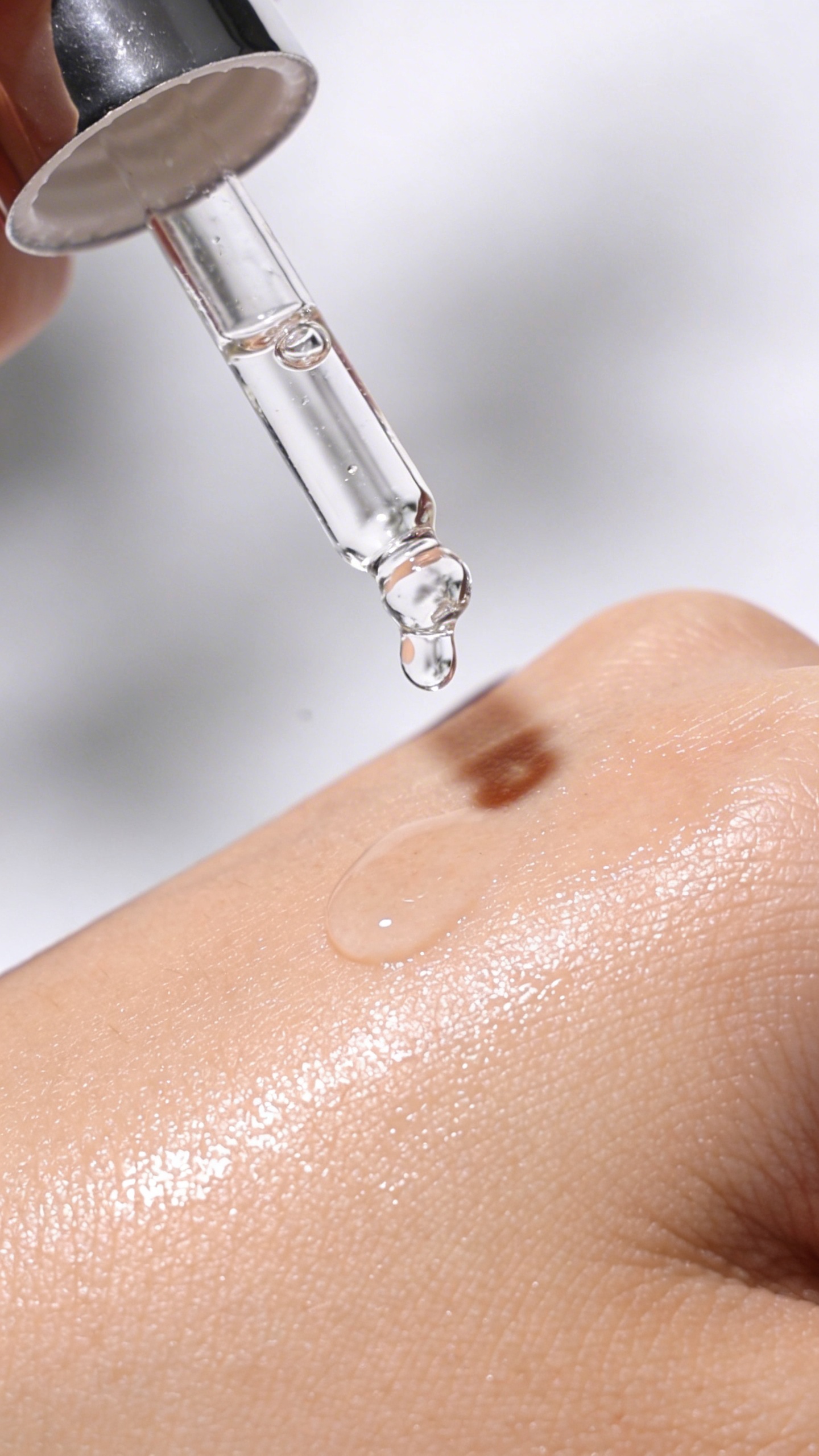 dropper of hyaluronic acid serum over dewy cheek, studio lighting